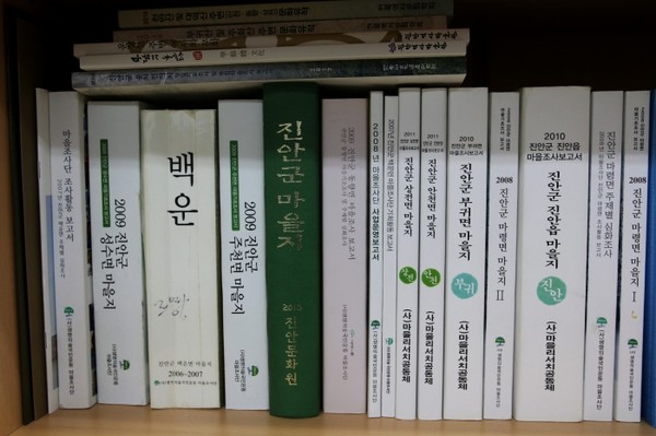 책상에 빼곡히 꽂힌 마을 자료들. 절반 이상은 정 사무국장이 쓴 보고서다.